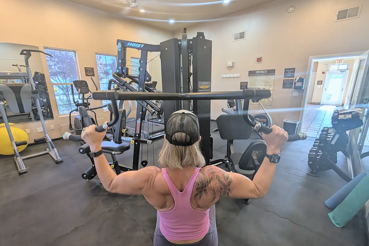 Jill from behind on a lat pulldown machine, back and shoulder muscles showing