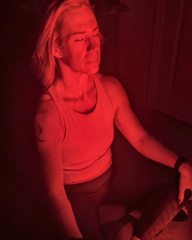 Jill sitting cross-legged in red light with her eyes closed