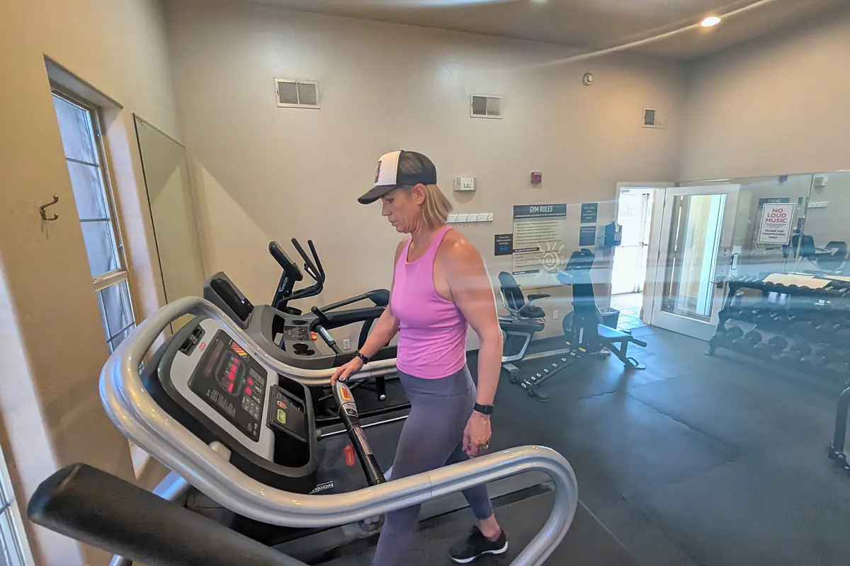 Jill stepping onto a treadmill in a small, quiet gym